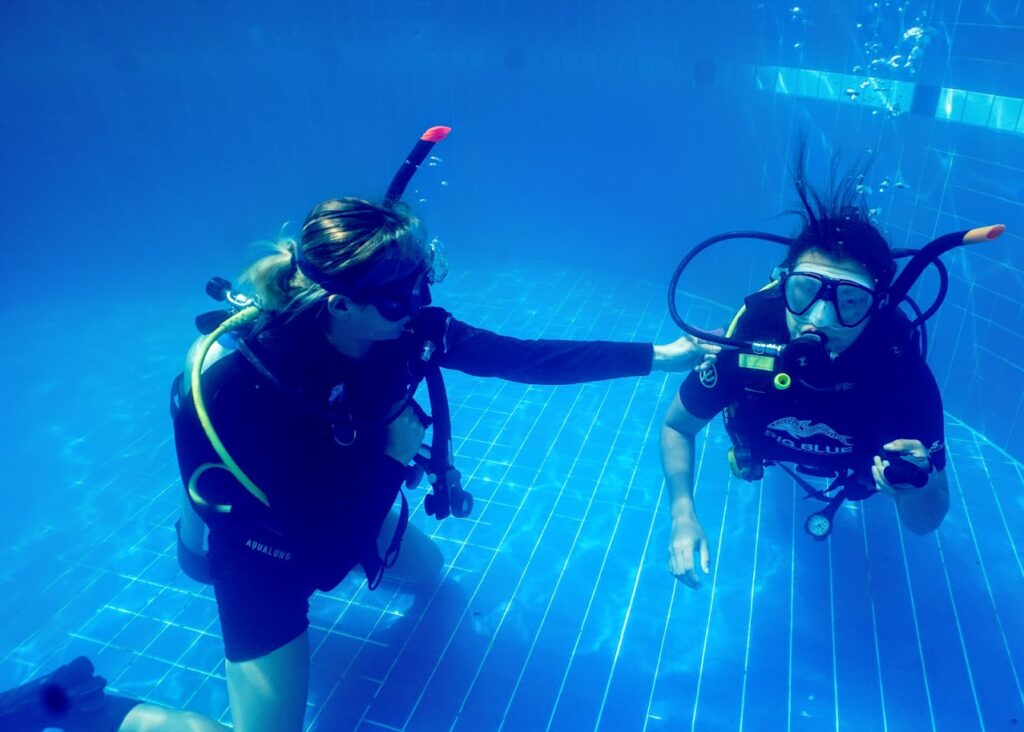 Beginner scuba diver learning skills in pool with instructor