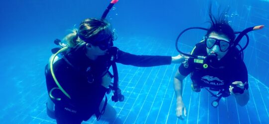 Beginner scuba diver learning skills in pool with instructor